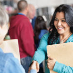 Female volunteer greeting woman at donation facility.
