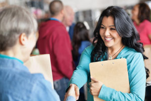 Female volunteer greeting woman at donation facility.