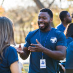 During a community cleanup event, a mid adult man gestures while talking with his friends.