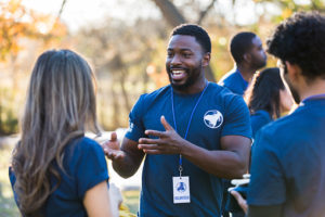 During a community cleanup event, a mid adult man gestures while talking with his friends.