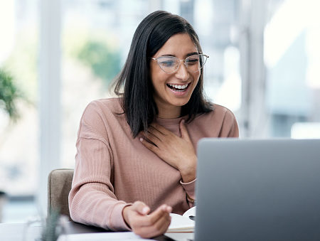 Shot of a young woman using a laptop and looking surprised while working from home